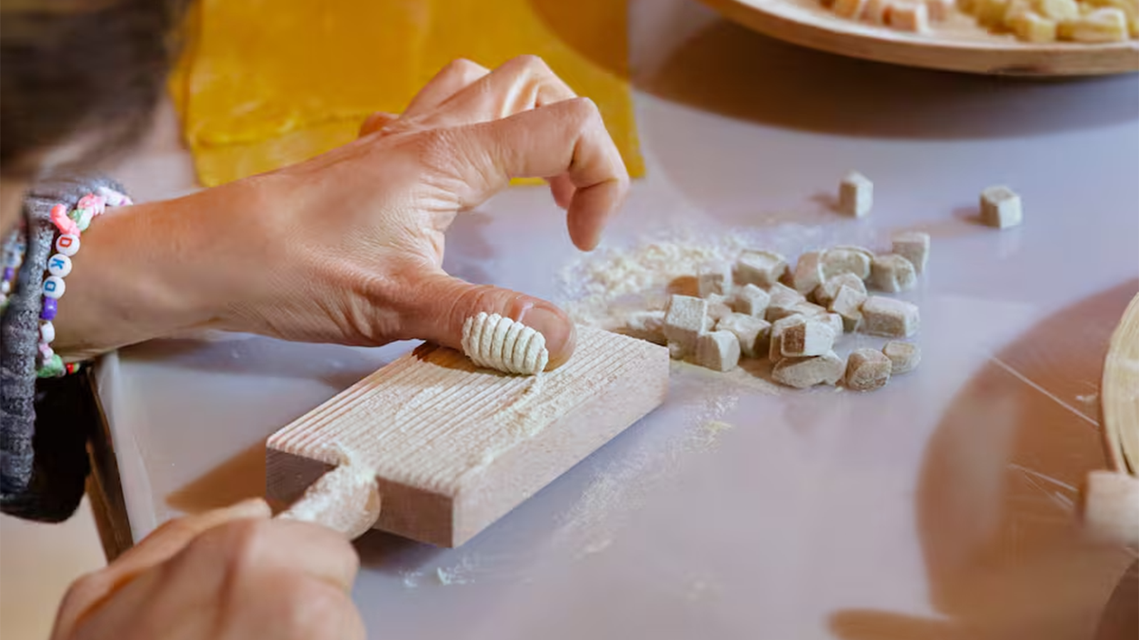 Mani che impastano pasta fresca con farina durante il corso hands-on di cucina italiana