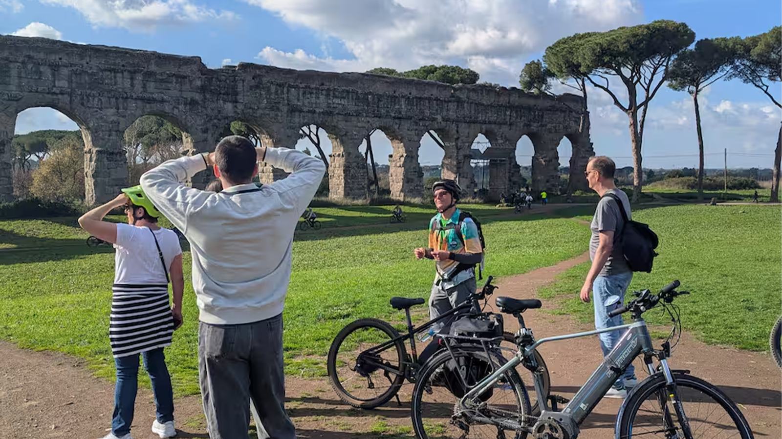 Maestosi archi dell'Acquedotto romano nel Parco degli Acquedotti con turisti in e-bike