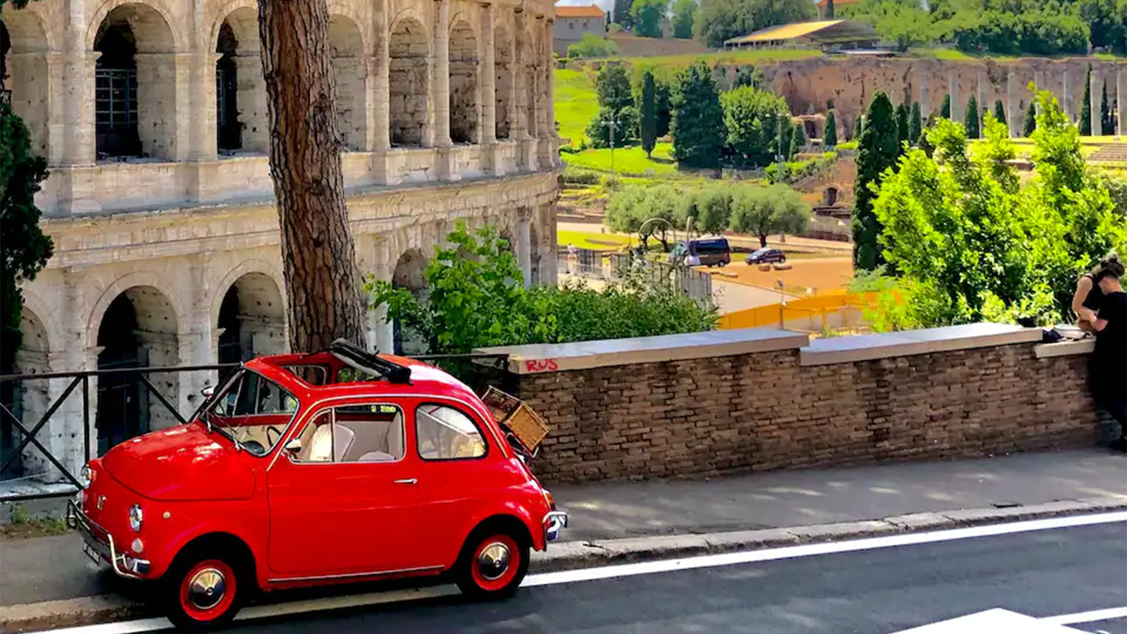 Fiat 500 vintage parcheggiata davanti al Colosseo durante sosta fotografica